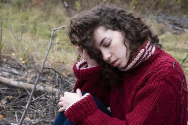 Sonbahar ormanında, sıcak örülü kazak giyen bir kız.