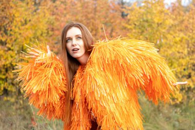 Kızıl saçlı genç kız sonbahar ormanının arka planında dans ediyor.