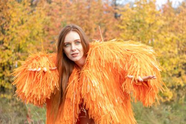 Kızıl saçlı genç kız sonbahar ormanının arka planında dans ediyor.