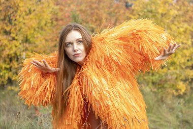 Kızıl saçlı genç kız sonbahar ormanının arka planında dans ediyor.