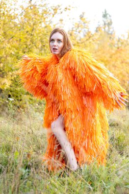 Kızıl saçlı genç kız sonbahar ormanının arka planında dans ediyor.