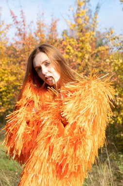 Kızıl saçlı genç kız sonbahar ormanının arka planında dans ediyor.