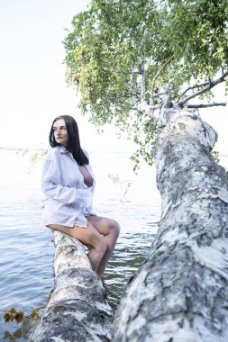 Suya düşen huş ağacında ıslak beyaz gömlekli genç bir kız.