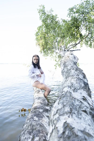 Suya düşen huş ağacında ıslak beyaz gömlekli genç bir kız.