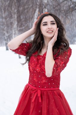 Karlı bir ormanın arka planında kırmızı elbiseli genç bir kız. Kış portresi