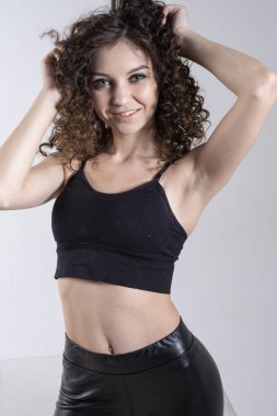 Açık arkaplanda parlak makyajlı kıvırcık bir genç kızın portresi. Stüdyo resmi.