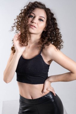 Açık arkaplanda parlak makyajlı kıvırcık bir genç kızın portresi. Stüdyo resmi.