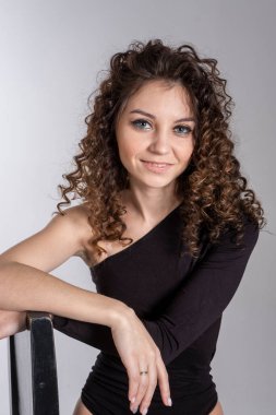 Kıvırcık saçlı ve parlak makyajlı genç bir kızın portresi. Stüdyo resmi.