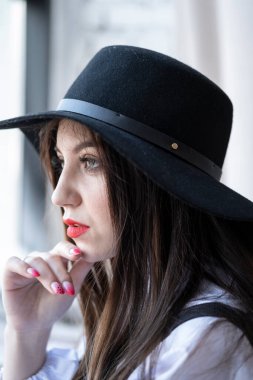 Parlak makyajlı ve şapkalı genç bir kızın portresi. Stüdyo resmi.