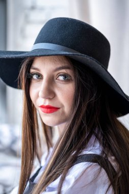 Parlak makyajlı ve şapkalı genç bir kızın portresi. Stüdyo resmi.