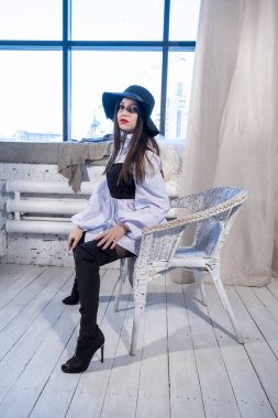 Parlak makyajlı ve şapkalı genç bir kızın portresi. Stüdyo resmi.