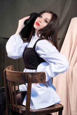 Parlak makyajlı ve sandalyede otururken poz veren güzel bir genç kız. Stüdyo resmi.