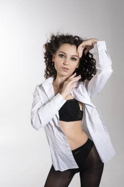 Beyaz gömlekli ve siyah iç çamaşırlı güzel bir genç kız. Işık arkaplanındaki stüdyo resmi