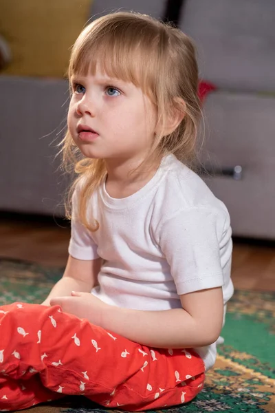 カーペットの上の部屋に座ってテレビを見ている女の子 — ストック写真