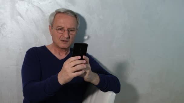 Älterer Grauhaariger Mann Blickt Auf Smartphone Bildschirm — Stockvideo