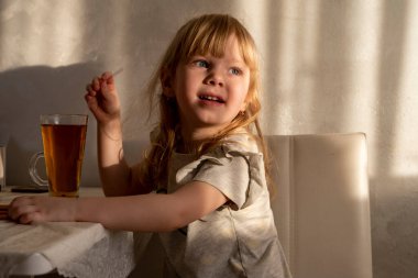 Çocuk, batan güneşin ışınlarında odada oturur.