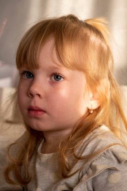 Çocuk, batan güneşin ışınlarında odada oturur.