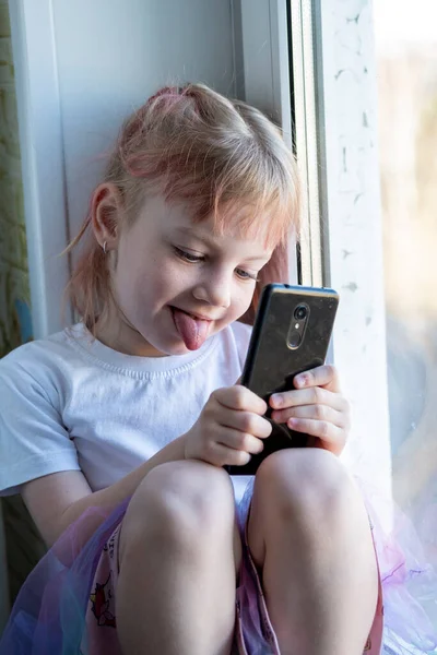 Çocuk Cep Telefonuyla Pencere Pervazında Oturuyor — Stok fotoğraf