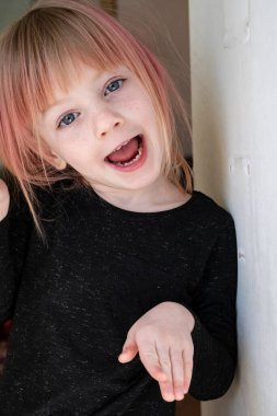 Yüzünde çiller olan küçük bir sarışın kameranın önünde surat yapıyor. Yakın plan portre.