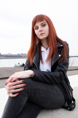 Beyaz gömlekli, deri ceketli, kızıl saçlı genç kız.