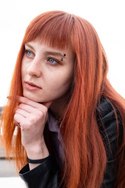 Beyaz gömlekli, deri ceketli, kızıl saçlı genç kız.