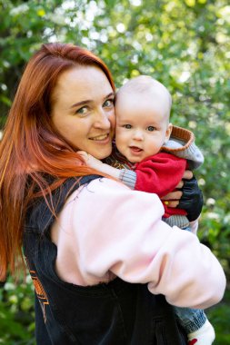 Anne parkta yürürken oğlunu kollarında tutuyor..