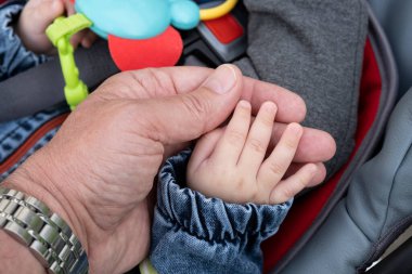 Bir adamın eli küçük bir çocuğun kalemini tutuyor.