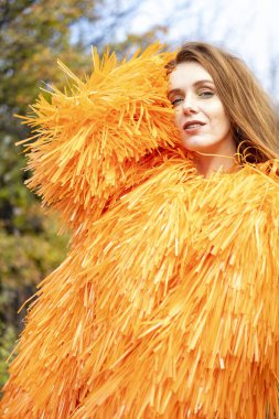 Sonbahar bahçesinde poz veren parlak elbiseli duygusal kız.