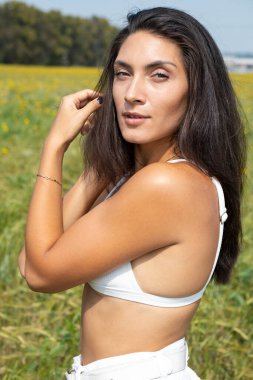 Beyaz elbiseli genç kız tarlada yürüyor.