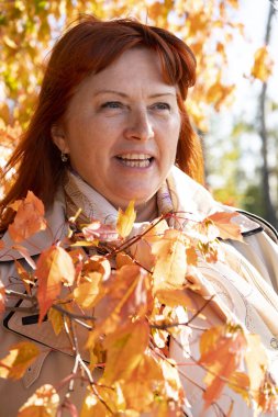 Yaşlı bir kadın sonbahar parkında yürüyor.