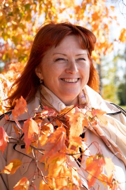 Yaşlı bir kadın sonbahar parkında yürüyor.