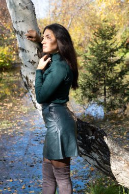 Göletin kenarında poz veren ince, esmer bir kız. Sonbahar