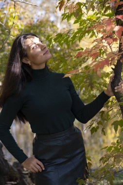 Sonbahar manzaralarının arka planında poz veren narin bir esmer.