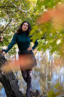 Sonbahar manzaralarının arka planında poz veren narin bir esmer.