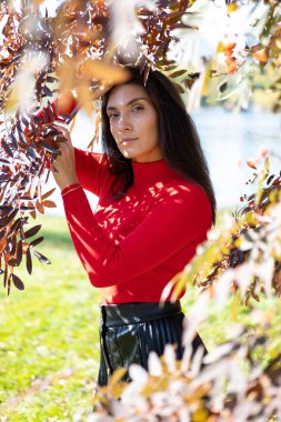 Sonbahar manzaralarının arka planında poz veren narin bir esmer.