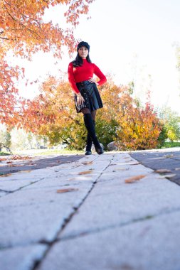 Renkli sonbahar yapraklarının arka planında poz veren şapkalı genç kız.