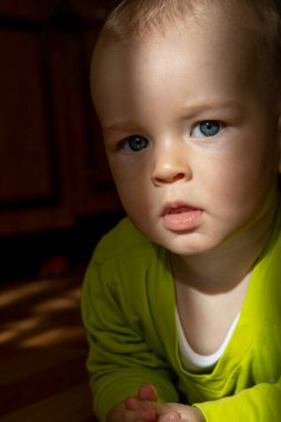 Karanlık bir odada, gün ışığının altındaki küçük duygusal çocuk.