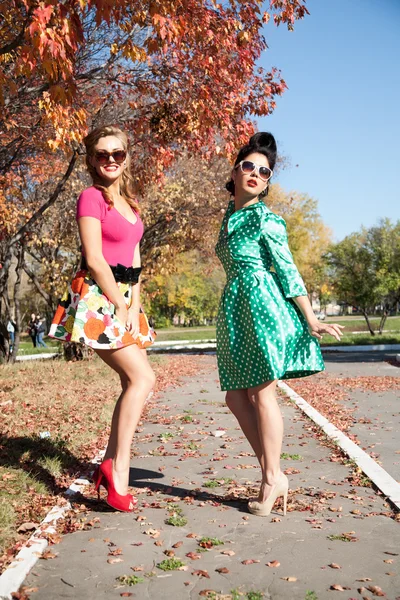 Two girls in colorful dresses walking in the autumn park — Stock Photo, Image