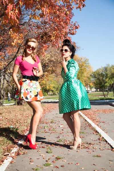 Two girls in colorful dresses walking in the autumn park — Stock Photo, Image