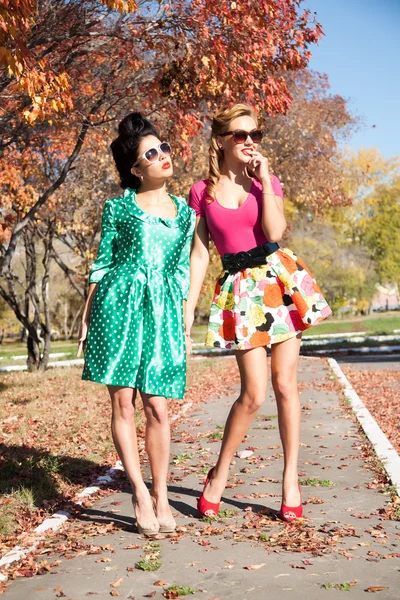 Two girls in colorful dresses walking in the autumn park — Stock Photo, Image