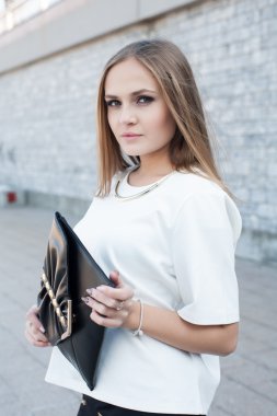 iş kadını bir duvara bir arka plan üzerinde debriyaj çanta