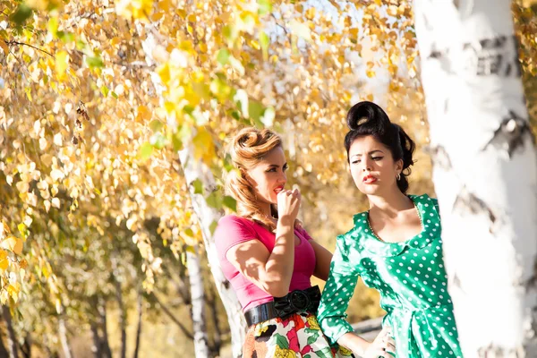 Zwei Mädchen auf dem Hintergrund der hellen Herbstblätter der Birke — Stockfoto