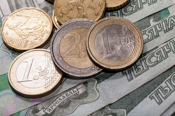 Euromunten op een achtergrond van een duizend roebels bankbiljetten — Stockfoto