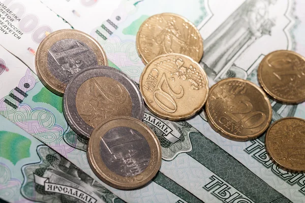 Monedas en euros sobre un fondo de mil rublos billetes —  Fotos de Stock