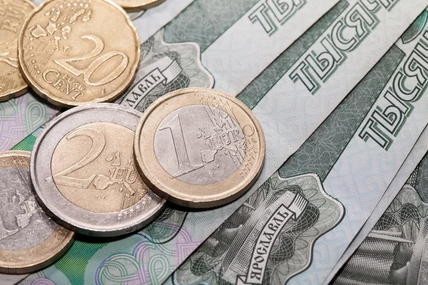 Monedas en euros sobre un fondo de mil rublos billetes — Foto de Stock