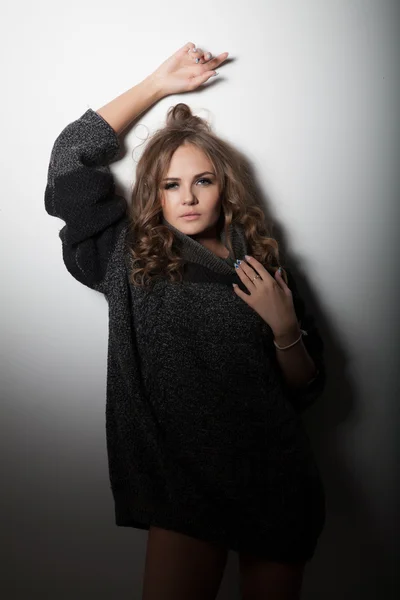 Ragazza in un maglione in piedi al muro bianco — Foto Stock