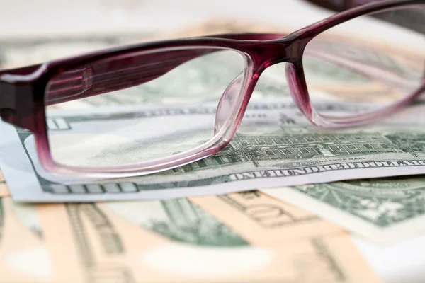Glasses on the background of US dollars banknotes — Stock Photo, Image