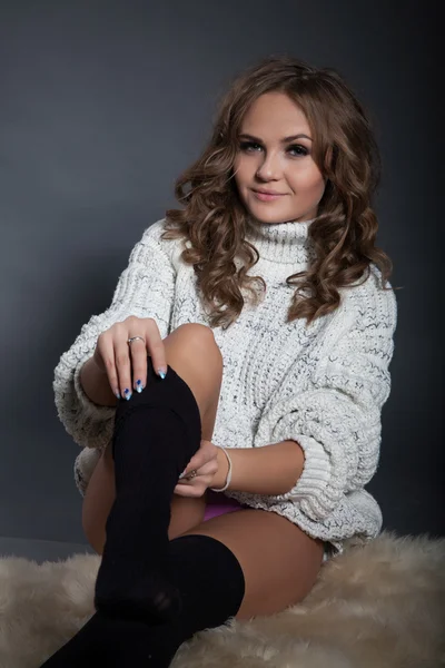 Ung flicka i en ylle tröja och svarta strumpor — Stockfoto