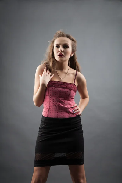 Meisje in een zwarte korte rok en blouse roze. studio portret — Stockfoto