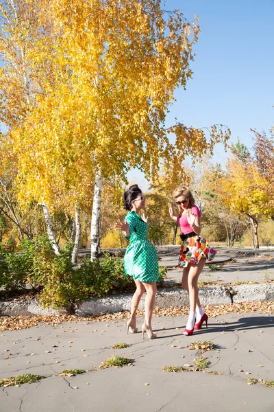 Дівчата в яскравому одязі танцюють в осінньому парку — стокове фото